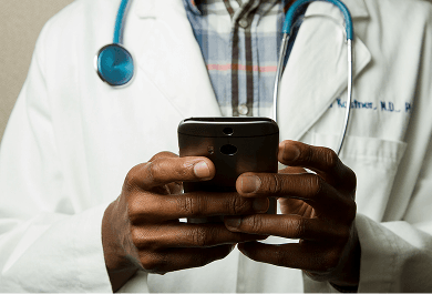 A doctor in a white coat holding a patient’s hands